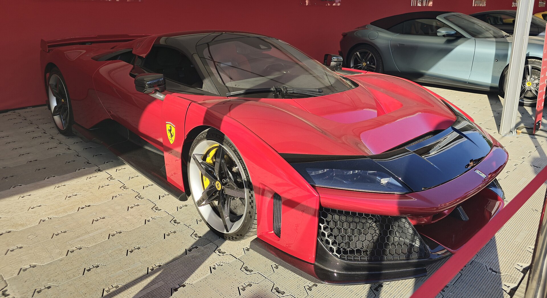 Front-Drei-Viertel-Perspektive mit Scuderia-Ferrari-Emblemen und gelben Hochleistungs-Bremssätteln